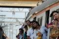 Woman passengers hanging from a moving train. - Sakshi Post
