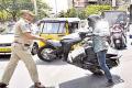 An enraged SI lifts the motorist’s vehicle with hand with an angry look at biker - Sakshi Post