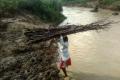 Naikpod woman crossing river with a load of firewood on her head Naikpod woman crossing river with a load of firewood on her head - Sakshi Post