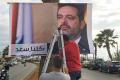 Workers hang a poster of Prime Minister Saad Hariri in the Lebanese capital Beirut - Sakshi Post