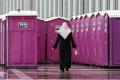 A woman walks past a row of portable toilets at a shelter for migrants inside a hangar of the former Tempelhof airport in Berlin, Germany, December 9, 2015. - Sakshi Post
