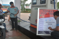 An employee updates fuel prices display board at a petrol pump - Sakshi Post