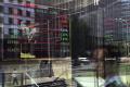People and office buildings are reflected on a brokerage houses window as an electronic board displaying stock trading index &amp;amp;nbsp; - Sakshi Post