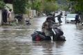 A woman trying to move her scooty in a waterlogged street - Sakshi Post