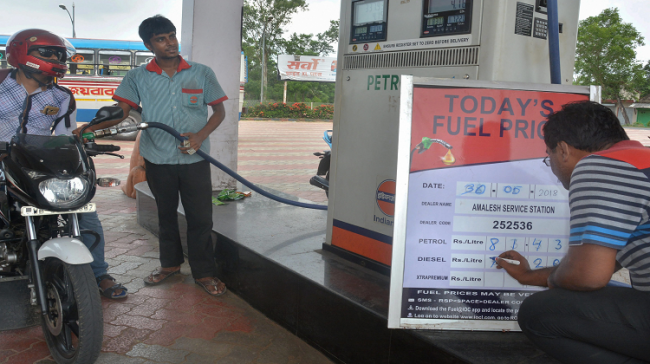 An employee updates fuel prices display board at a petrol pump - Sakshi Post